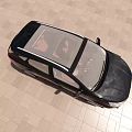 Top View of Black Car with Two People Inside Parked on Light Colored Tiled Floor