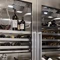 Stainless Steel Wine Cooler Interior With Wine Bottles And Glasses On Multiple Shelves
