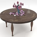Round Wooden Dining Table Set with Gold Patterns Blue Vase Pink Flowers and Scattered Petals