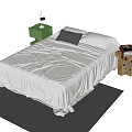 Double Bed with Light Colored Bedspread Black Pillow and Green Nightstand on Dark Carpet