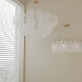 Modern Chandeliers In White Wall Interior With Circular Transparent Discs And Cylindrical Shades