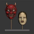 Red Demon And Light Colored Human Face Costume Masks On Black Base With Golden Stands