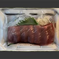 Fresh Tuna Sashimi Slices Neatly Arranged On White Plate With Green Garnish