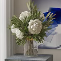 White Peonies and Green Leaves in Transparent Vase on Table with Blue Abstract Painting