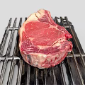 Fresh Ribeye Beef Steak On Black Grill With Juicy Red Meat And Fat