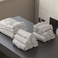 Neatly Stacked Folded And Rolled Towels On Gray Table With Light Wall