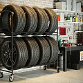 Organized Garage With Tire Rack Holding Stacked Tires Against Brick Wall And Tool Storage Shelves