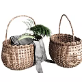 Two Handwoven Wicker Storage Baskets With Gray Fabric And Green Foliage