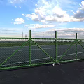 Green Diamond Mesh Fence With Top Barbed Wire Against Blue Sky White Clouds And Grassland