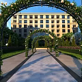Garden Landscape Design With Flower Covered Arches Stone Pathway Greenery And Building