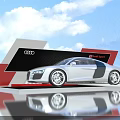 Silver Audi R8 Spyder on Display Platform with Red Black Design and Blue Sky Clouds