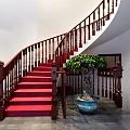 Elegant Spiral Staircase With Red Carpet Wooden Handrail And Green Plants Against White Walls