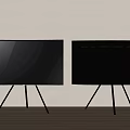 Two Black Modern TVs with Tripod Stands on Wooden Floor Against Neutral Wall