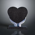 Black Heart Shaped Decorative Ornament Held By White Hands On Black Base