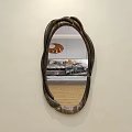 Wall Mounted Wooden Frame Mirror With Irregular Shape Reflecting Sofa And Wooden Floor