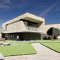 Modern Office Building With Stone Facade Large Windows Balcony And Lush Lawn Trees