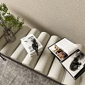 Beige Quilted Footstool with Green Plant Glass Vase and Open Magazines in Living Room