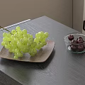 Green Grapes on Wooden Plate and Dark Cherries in Glass Bowl on Gray Table