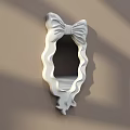White Decorative Mirror with Bow Shaped Frame Wavy Edges on Light Brown Wall with Shadows