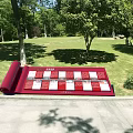 Red Scroll Shaped Sculpture With Grid Pattern On Green Lawn In Park 3d model