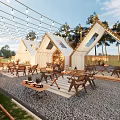 Outdoor Garden Landscape With Tent Like Canopies Wooden Tables Palm Trees And String Lights