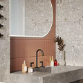 Modern Terrazzo Bathroom Interior With Illuminated Rounded Mirror And Warm Terracotta Accent Wall