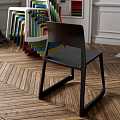 Black Leisure Chair With Colorful Stacked Chairs On Wooden Herringbone Floor Interior