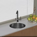 Black Round Kitchen Sink With High Arc Faucet On White Countertop And Glass Fruit Bowl