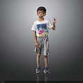Little Boy In Gray Background Wearing White T-shirt Gray Shorts Blue Sneakers And Peace Sign