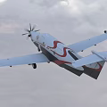 Passenger Plane Flying With Propeller And Landing Gear In Blue Sky With Clouds