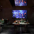 Modern Bar Interior With TV Screen Performers Green Chairs And Trophies On Tables