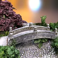 Stone Arch Bridge Surrounded By Red Shrubs Green Plants And Pebble Ground With Sunset Glow