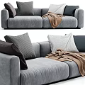 Cozy Gray Three Seater Sofa With Plush Cushions And Brown Throw Blanket