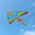 Bright Colorful Kite Flying High In Clear Blue Sky With Long Tail