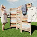 Woman Wearing White Towel Standing on Green Grass Next to Wooden Screen with Hanging Clothes