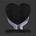 Black Heart Shaped Decorative Ornament Held By White Hands On Black Base