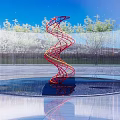 Spiral Red And Blue Sculpture In Circular Pool With Transparent Fence Green Trees Blue Sky