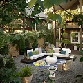 Cozy Garden Courtyard With Outdoor Sofa Colorful Pillows Lush Green Plants And Pebble Flooring