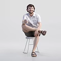Man sitting on stool holding cup wearing white shirt shorts and sandals against white background