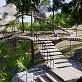Scenic Park Landscape With Circular Wooden Walkway Trees Seating And Lush Greenery