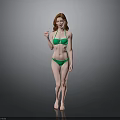 Woman with red hair wearing green bikini standing against gray background barefoot in natural pose