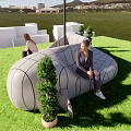 Airplane Shaped Public Chair On Green Lawn With People Sitting And Potted Plants