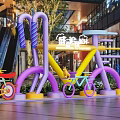 Colorful Bicycle Art Installation Photo Spot In Modern Mall With Vibrant Colors And Green Plants