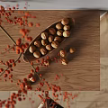 Decorative Ceramic Vessel Holding Nuts And Red Berries On Wooden Tray Surface