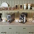 Stylish Kitchen Countertop With Various Coffee Machines Wall Shelves And Storage Cabinets