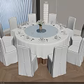 Modern Round Dining Table Set With White Tablecloth Flower Vase And White Surrounding Chairs