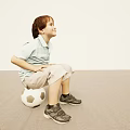 Young Boy Sitting On Soccer Ball In Light Colored Room With Striped Shirt And Sneakers