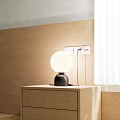 Modern Simple Table Lamp With Spherical White Shade And Black Base On Wooden Cabinet