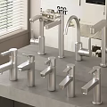Multiple Modern Stainless Steel Faucets Display On Gray Countertop With Window