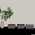 Three Vintage Radios On Black Table With White Vase Green Plant And Light Colored Wall